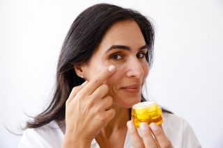 אישה מורחת קרם פנים על טהרת דבש המנוקה